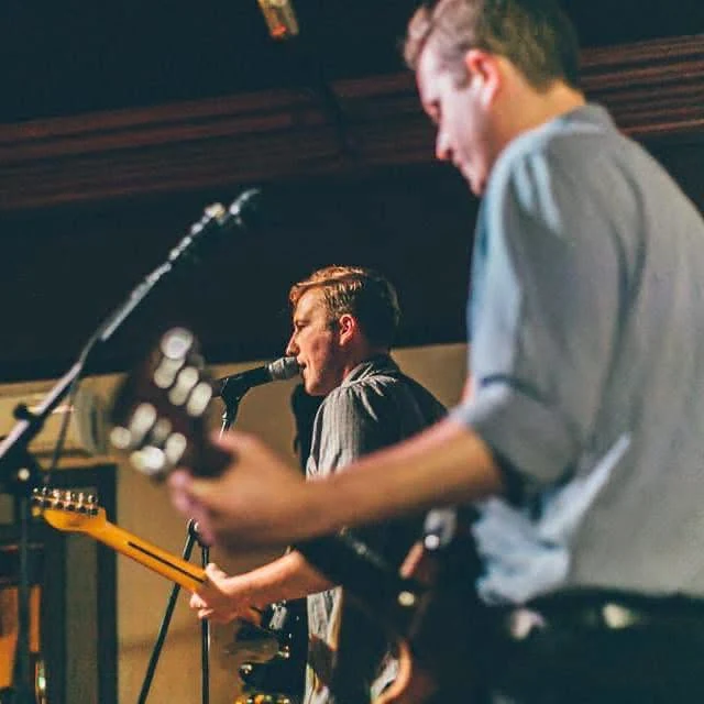 Musicians singing and playing guitar at a live performance