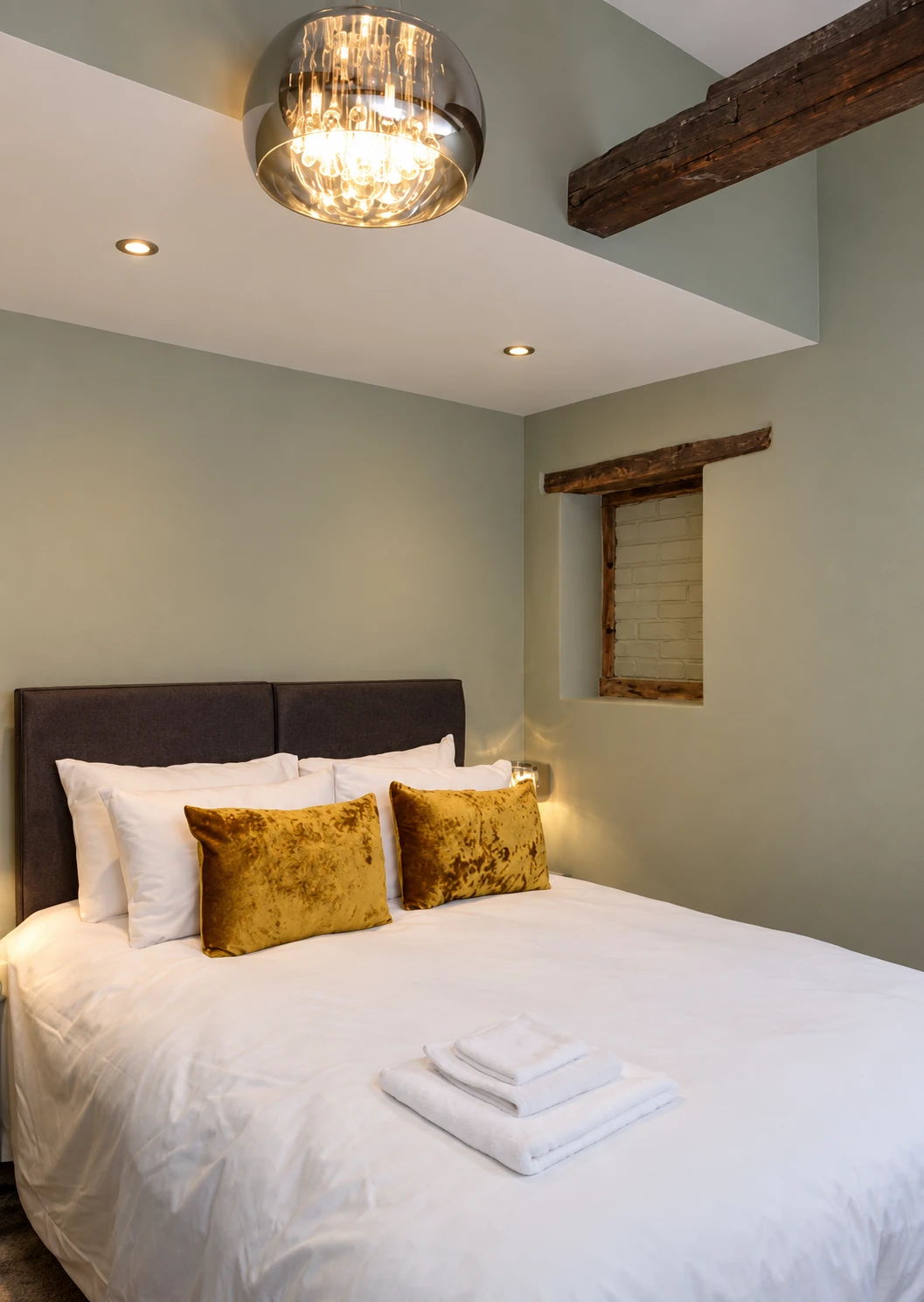 Bedroom with exposed beams, a glass pendant and golden cushions